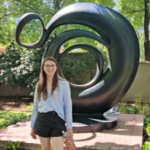Courtney Thomas in front of a large spiraling metal sculpture